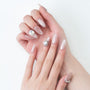 Hand with almond-shaped nude press-on nails, accent nails feature large rhinestones.