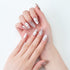 Close-up of hands with metallic silver long nails featuring 3D heart designs on white background