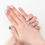 Hand with short, oval press-on nails in white, green marble and silver swirl design