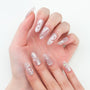 Hand with long, glossy, iridescent press-on nails featuring 3D swirl and star accents.