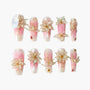 Handmade press-on nails with pink and white ombre, 3D floral designs, and gold accents