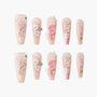 Handmade pink press-on nails with 3D floral designs, butterfly art, gems, and glitter accents.