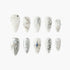 Set of white and silver decorative artificial nails with pearl and rhinestone accents, intricate designs