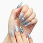 Hand with silver press-on nails, white butterfly accents, and blue glitter design