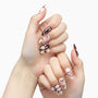 Hand-painted almond press-on nails with red bows, hearts, and holiday-themed designs on white and maroon base.