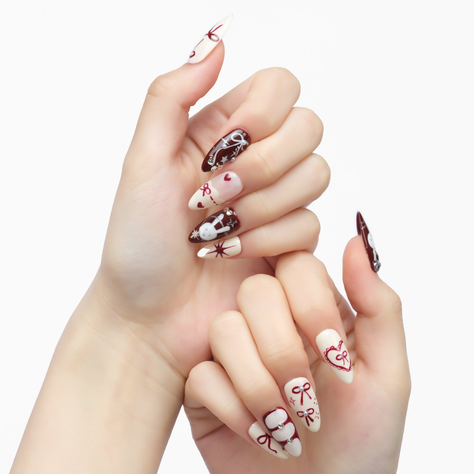 Hand-painted almond press-on nails with red bows, hearts, and holiday-themed designs on white and maroon base.
