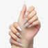 Close-up of hands with long almond-shaped nails featuring white and silver 3D floral and pearl nail art design