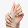 Close-up of hands with long almond-shaped nails featuring white and silver 3D floral and pearl nail art design