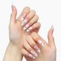 Hand with pink and white press-on nails featuring 3D floral accents, almond shape, salon style