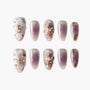 Elegant nail set with beige and purple ombre, 3D floral designs, and rhinestone accents