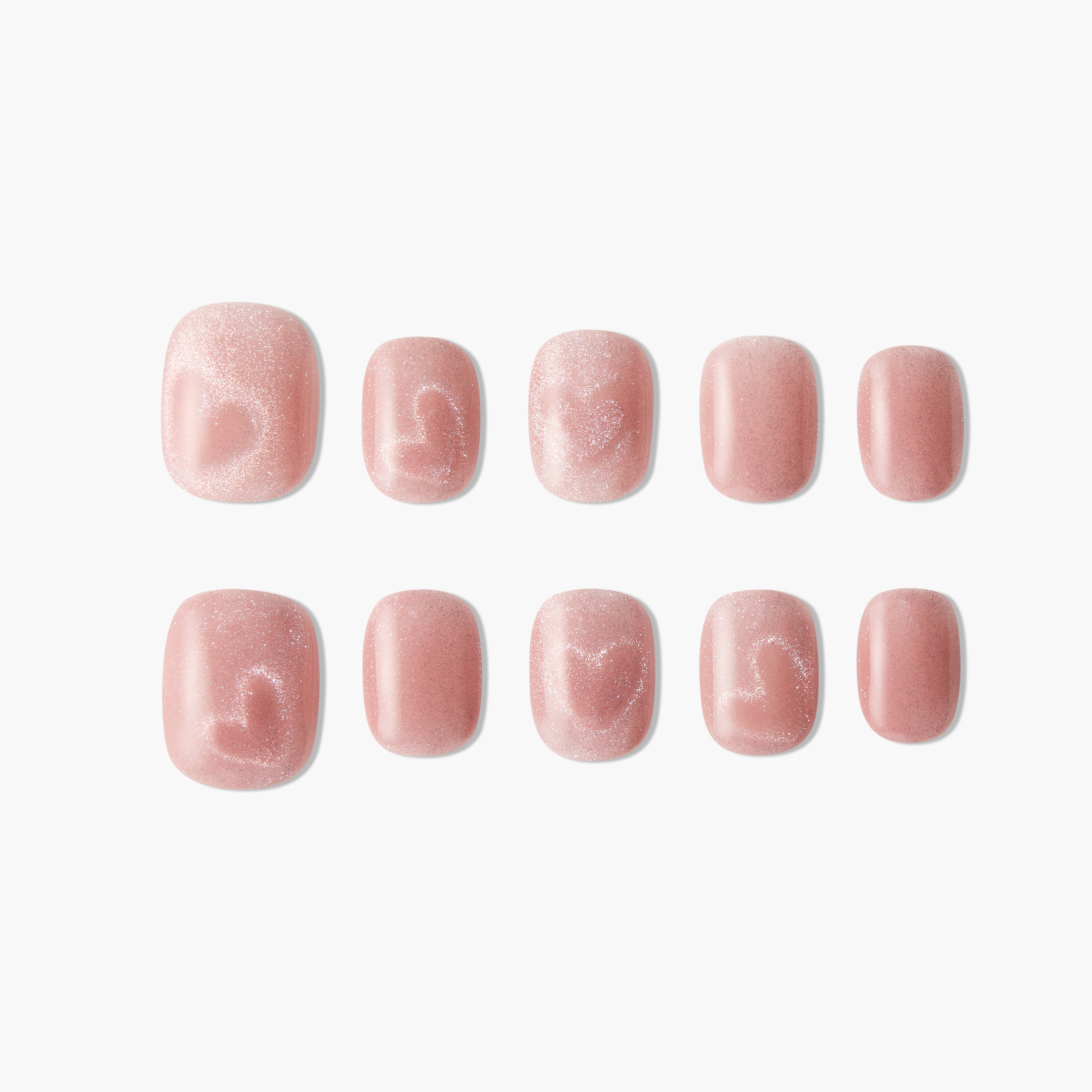 Set of glittery pink press-on nails with subtle heart designs on a white background