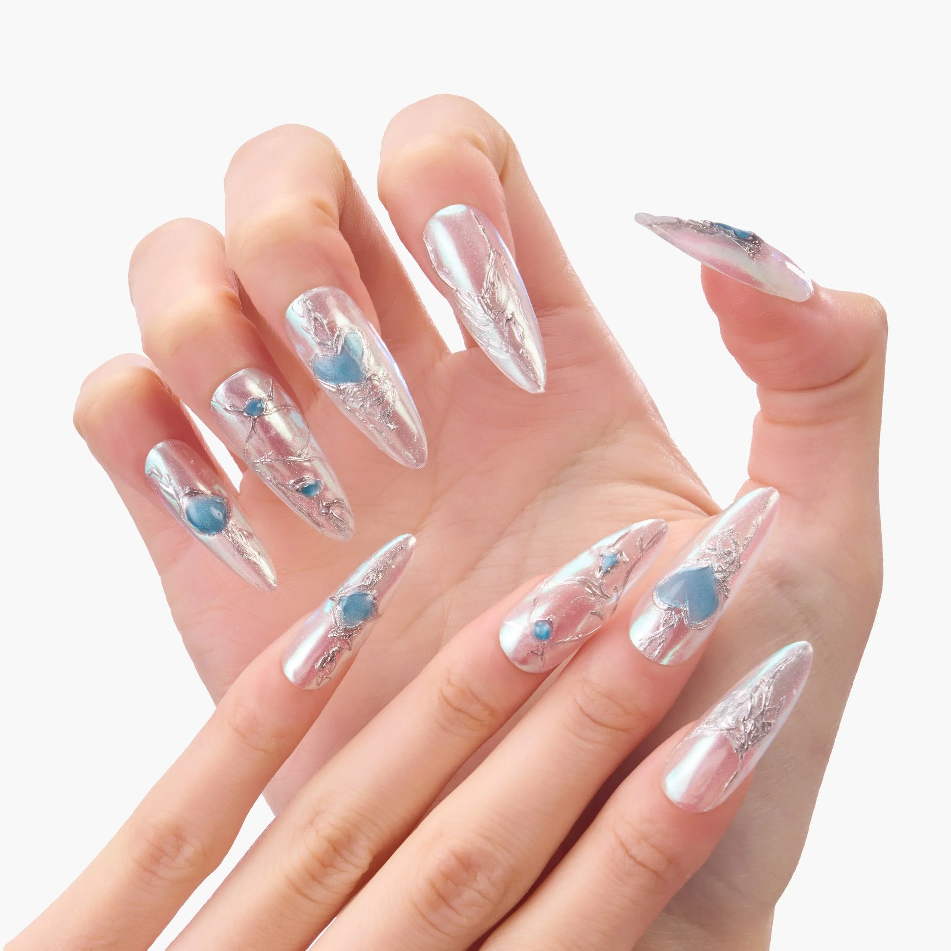 Hand with long press-on nails, clear with silver foil and blue heart-shaped accents.