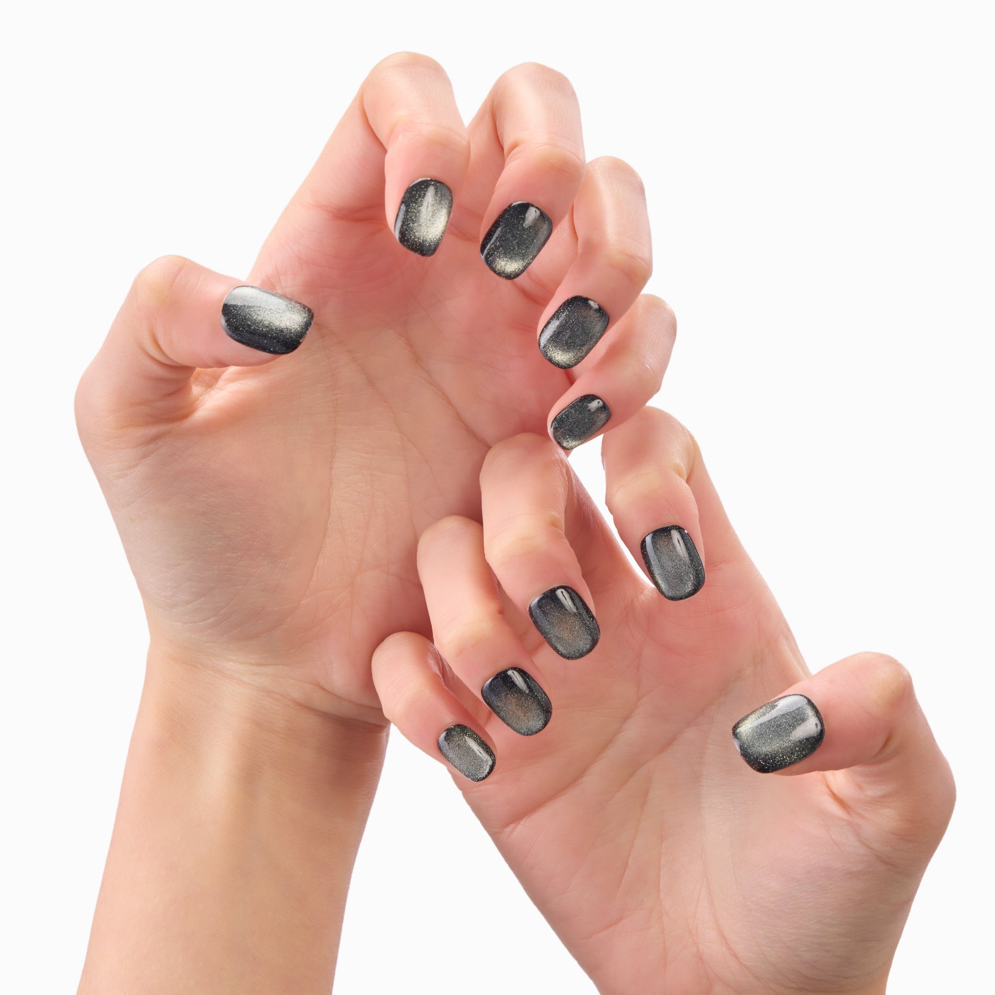 Hands with glossy black and silver ombre press-on nails against a white background
