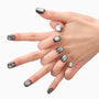 Hand with metallic black press-on nails, square shape, on a white background.