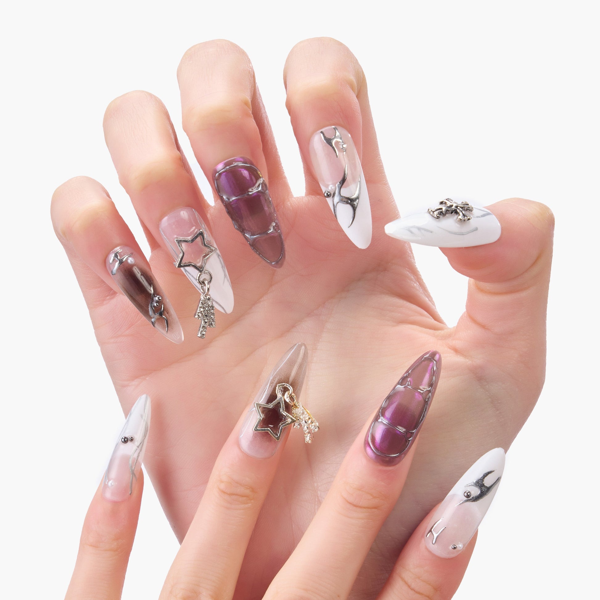 Hand with long press-on nails in purple, white, and marble designs, star and chain embellishments