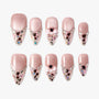 Set of pink glittery press-on nails with heart-shaped jewels, bows, and multicolor confetti accents
