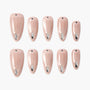 Set of nude pink press-on nails with silver teardrop and rhinestone accents on white background