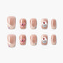 Set of glittery nude fake nails with cupcake and heart designs on white background