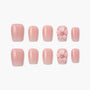 Handmade pink press-on nails with 3D flower and rhinestone accent, arranged on white background