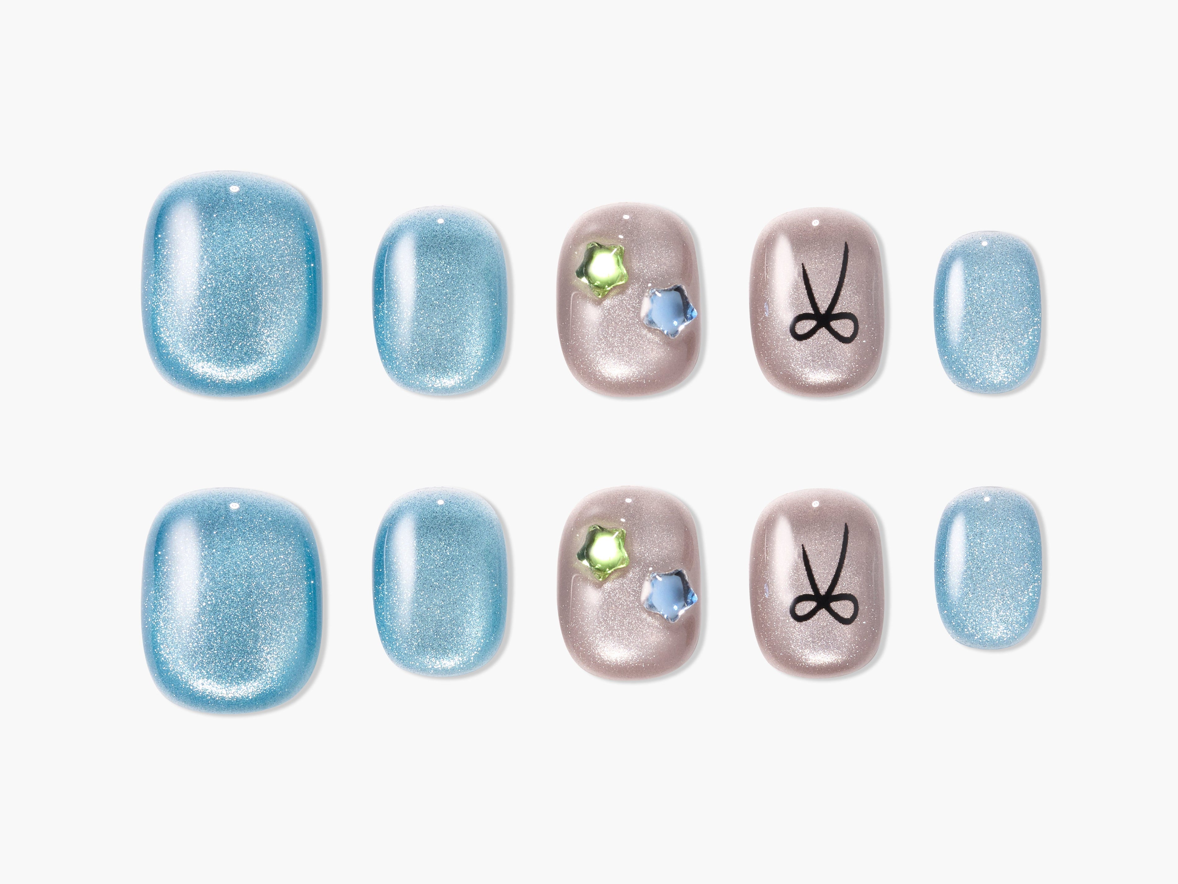 Set of glittery blue and beige press-on nails with star-shaped gems and black scissors design