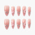 Set of pink ombre press-on nails with heart-shaped and wing embellishments on white background