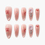 Set of pink press-on nails with red floral and crystal embellishments on white background