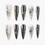 Long stiletto press-on nails in glossy white and metallic silver with 3D abstract accents
