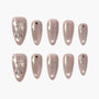 Set of sparkly nude press-on nails featuring silver bow, heart, and star designs