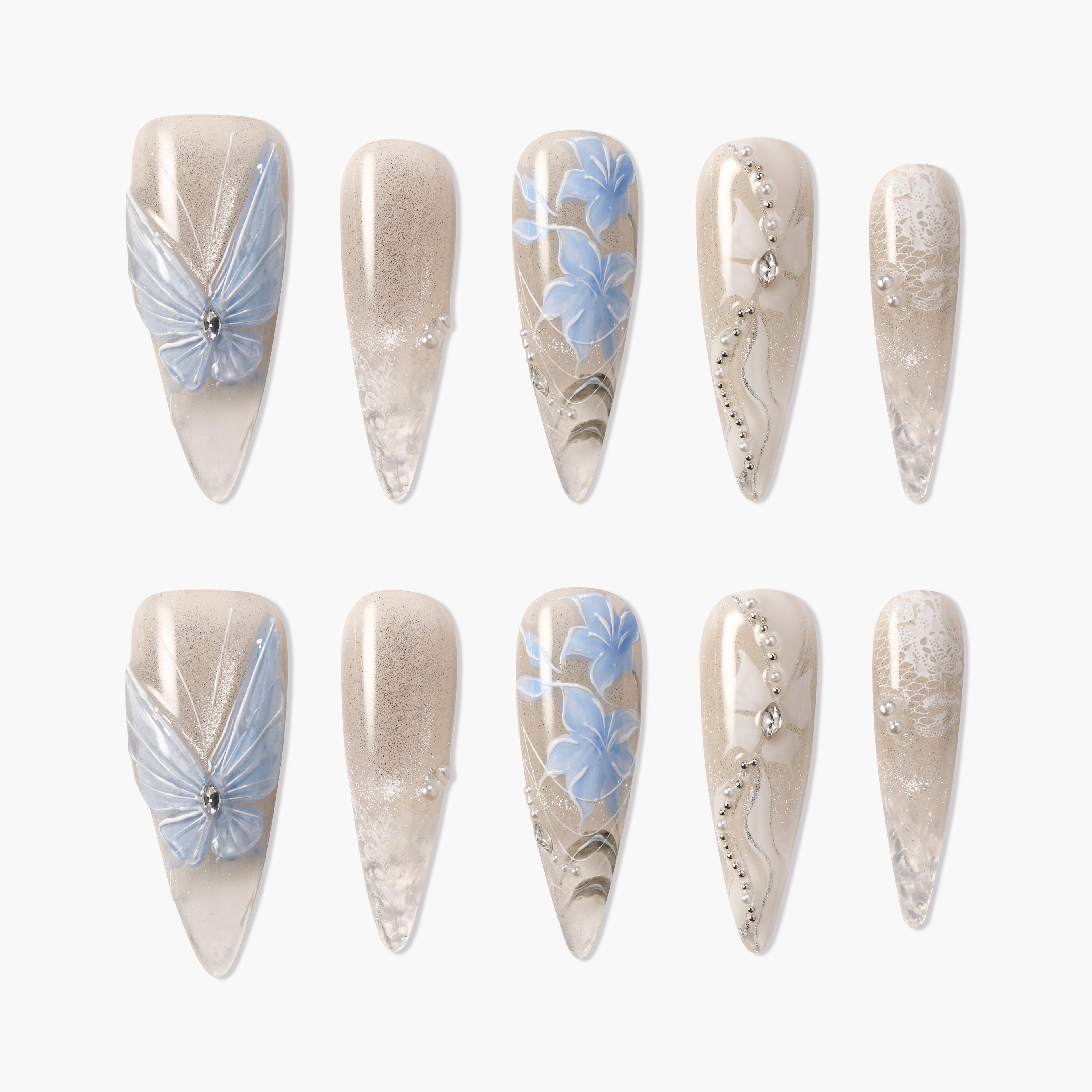 Set of beige press-on nails with blue butterfly, floral patterns, pearls, and rhinestone accents
