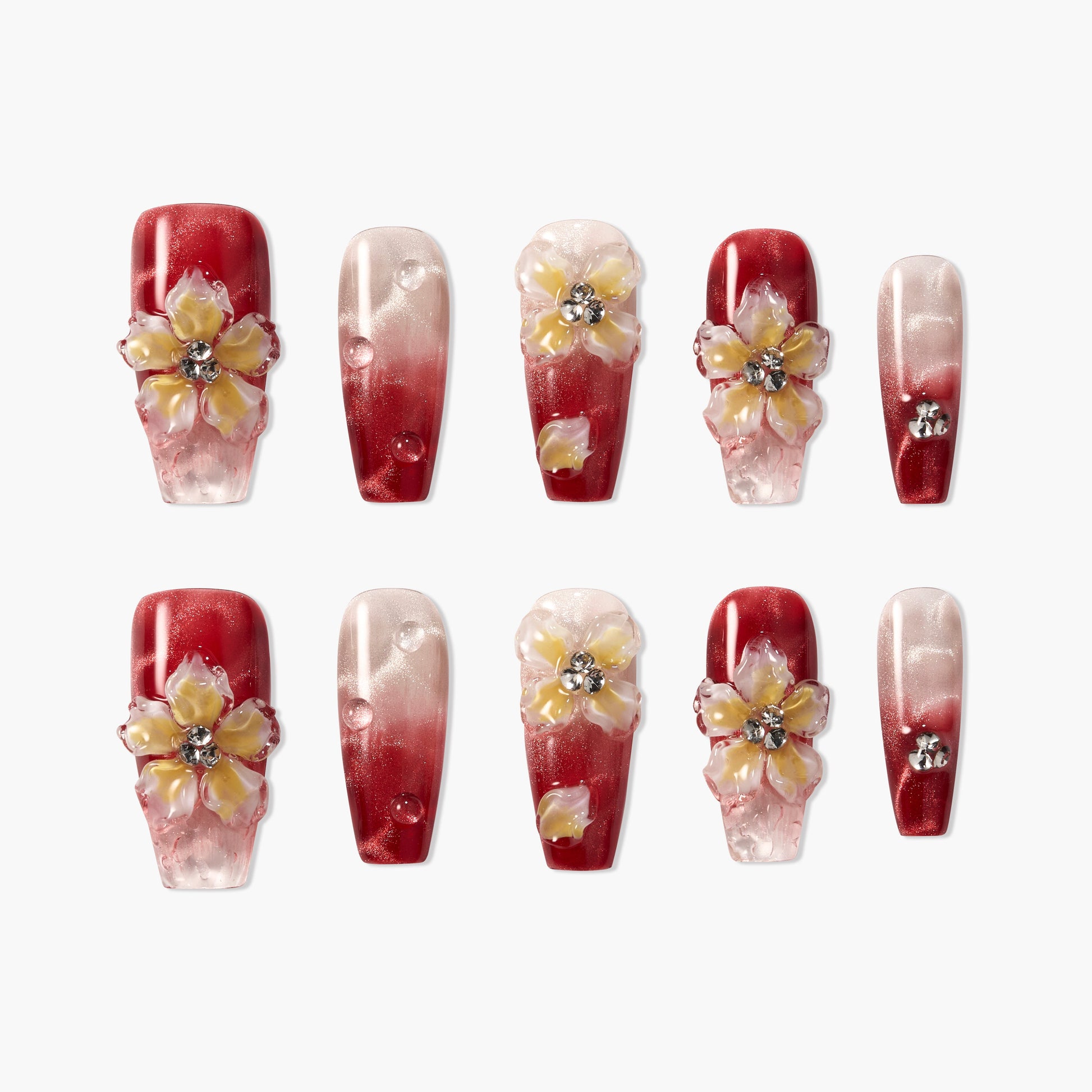 Red and pink ombre press-on nails with 3D floral accents and rhinestones, arranged on a white background.