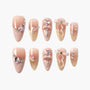 Elegant press-on nails in nude and gold gradient with pink gems, bows, and rhinestone accents