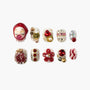 Set of 10 intricate press-on nails with red, gold, pearls, heart, flower, and glitter designs on white background