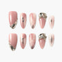 Set of pink press-on nails with glitter accents and rhinestone embellishments on white background