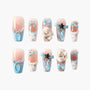 Set of press-on nails with blue bows, hearts, pearls, star charms, and bunny decorations on nude base
