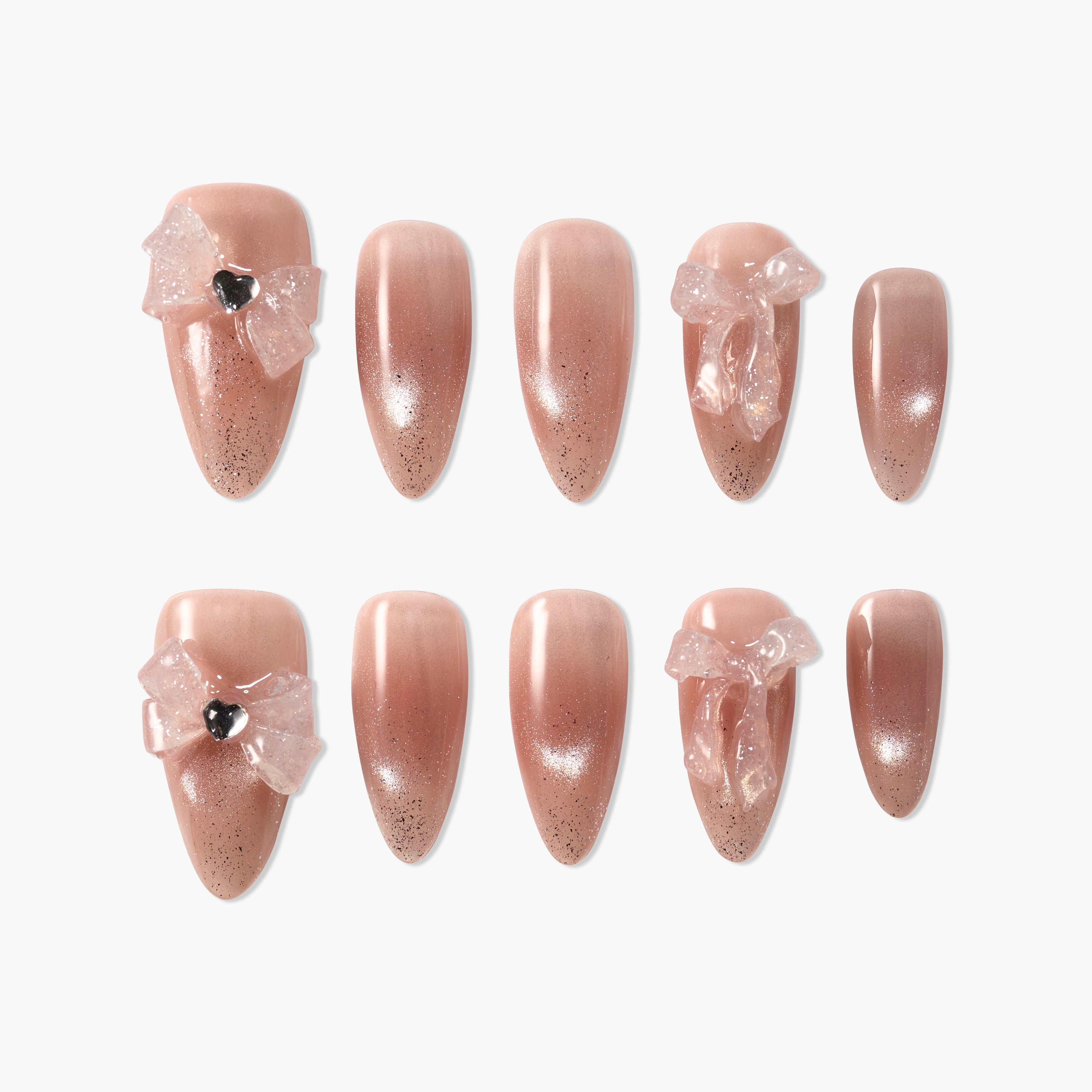 Set of nude ombre press-on nails with black glitter and clear bow accents, heart-shaped detail