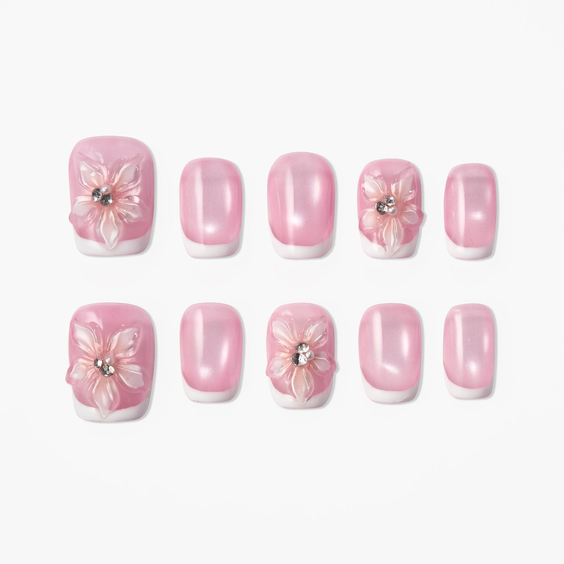 Pink press-on nails with white 3D floral accents and rhinestone details, glossy finish