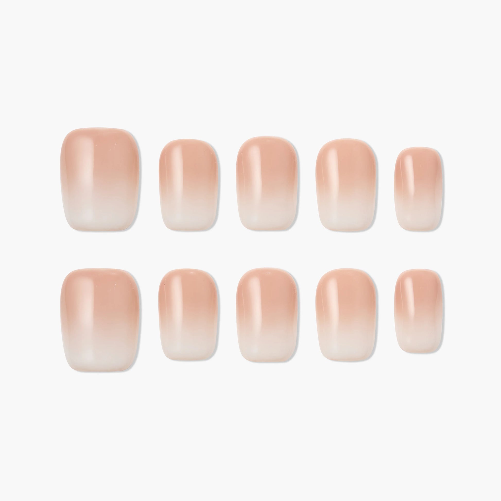 Set of nude ombre press-on nails with a glossy finish on white background