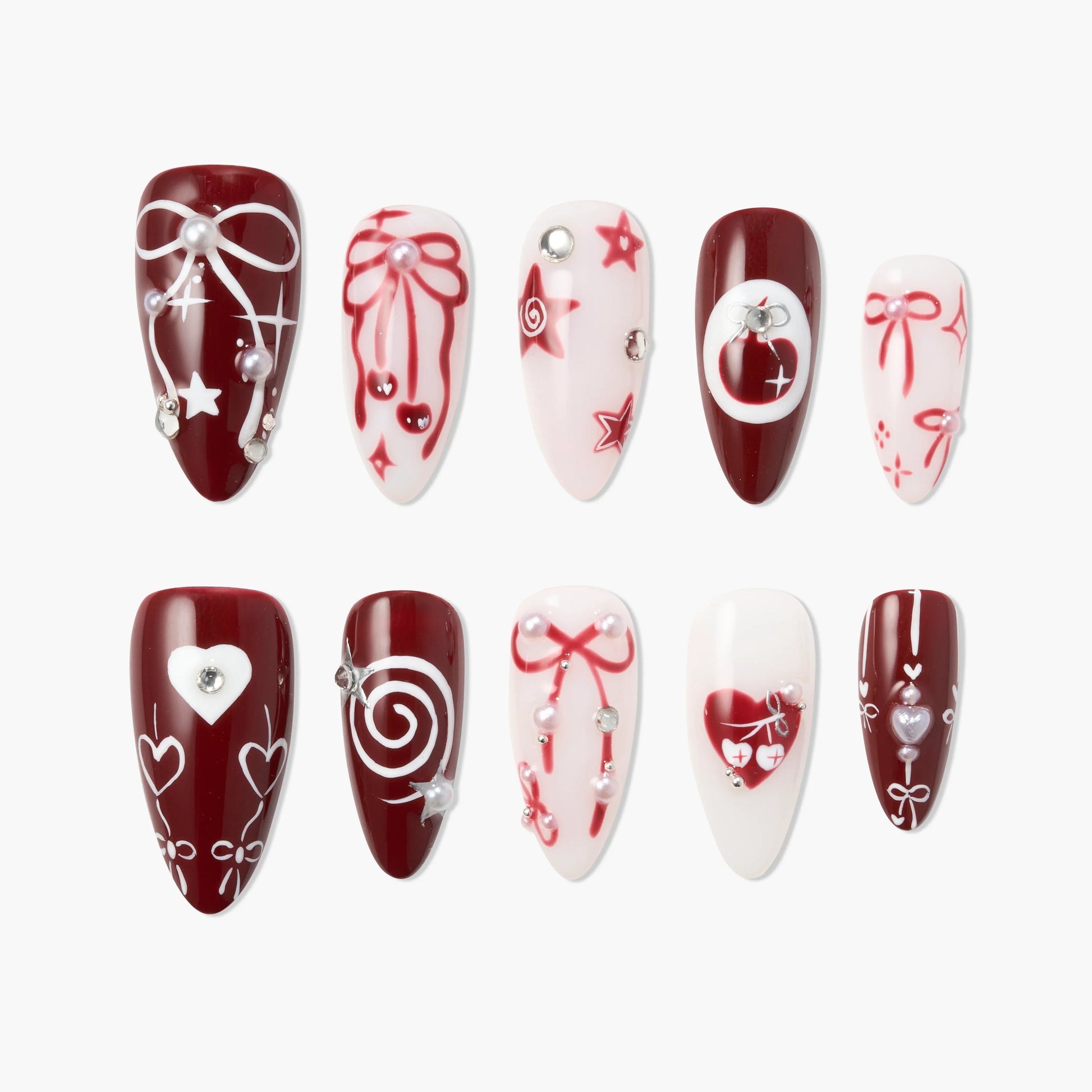 Red and white press-on nails with bows, hearts, stars, pearls, and gemstone accents