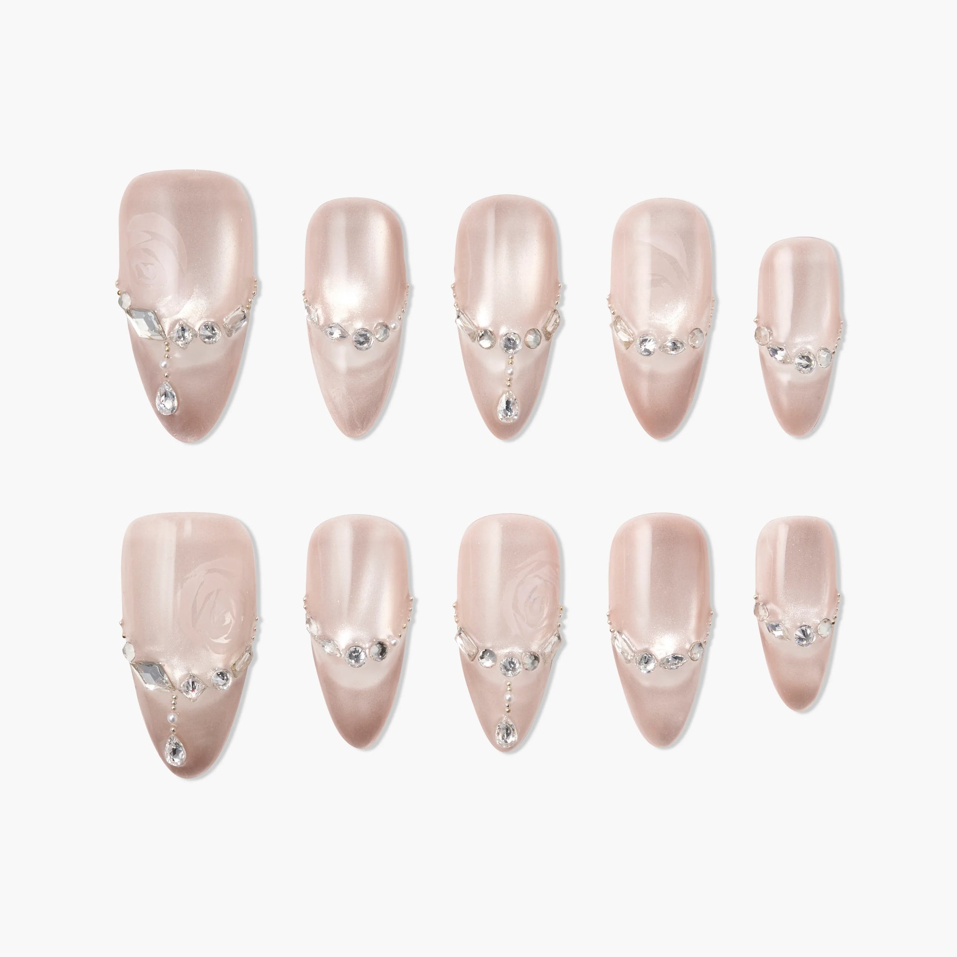 Glossy nude press-on nails with rhinestone and pearl accents, arranged on a white background.