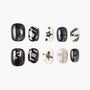 Black and white press-on nails with graphic art, stars, crosses, and metallic accents
