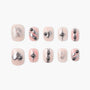 Press-on nails set with metallic silver heart, stripe, and stud accents on pink nude base.