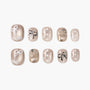 Beige press-on nails with bows, polka dots, and 3D crown accents, arranged on white background.