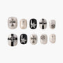 Glitter press-on nails set with silver cross, star, and stud accents in black and pearl tones