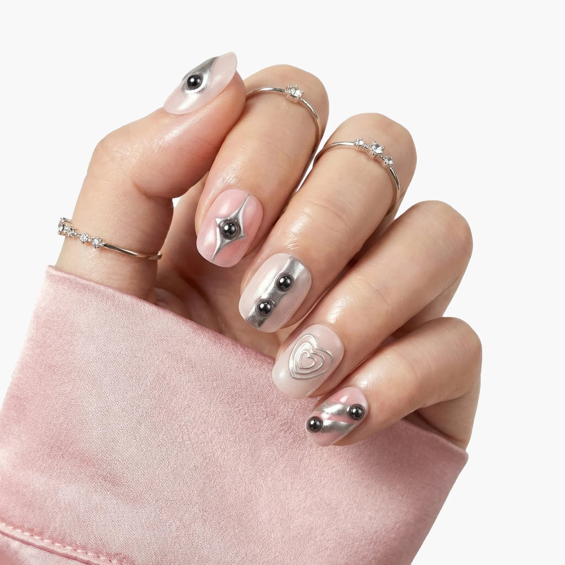Hand with silver 3D press-on nails, metallic accents, and minimalist gemstone rings