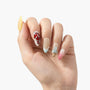 Hand wearing colorful handmade press-on nails with fruit and abstract designs