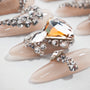 Nude press-on nails with large rhinestones and crystal embellishments, glossy finish