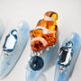 Blue press-on nails with crystal embellishments and a 3D orange fish design