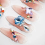 Handmade press-on nails with nude pink base, adorned with colorful crystals and rhinestones