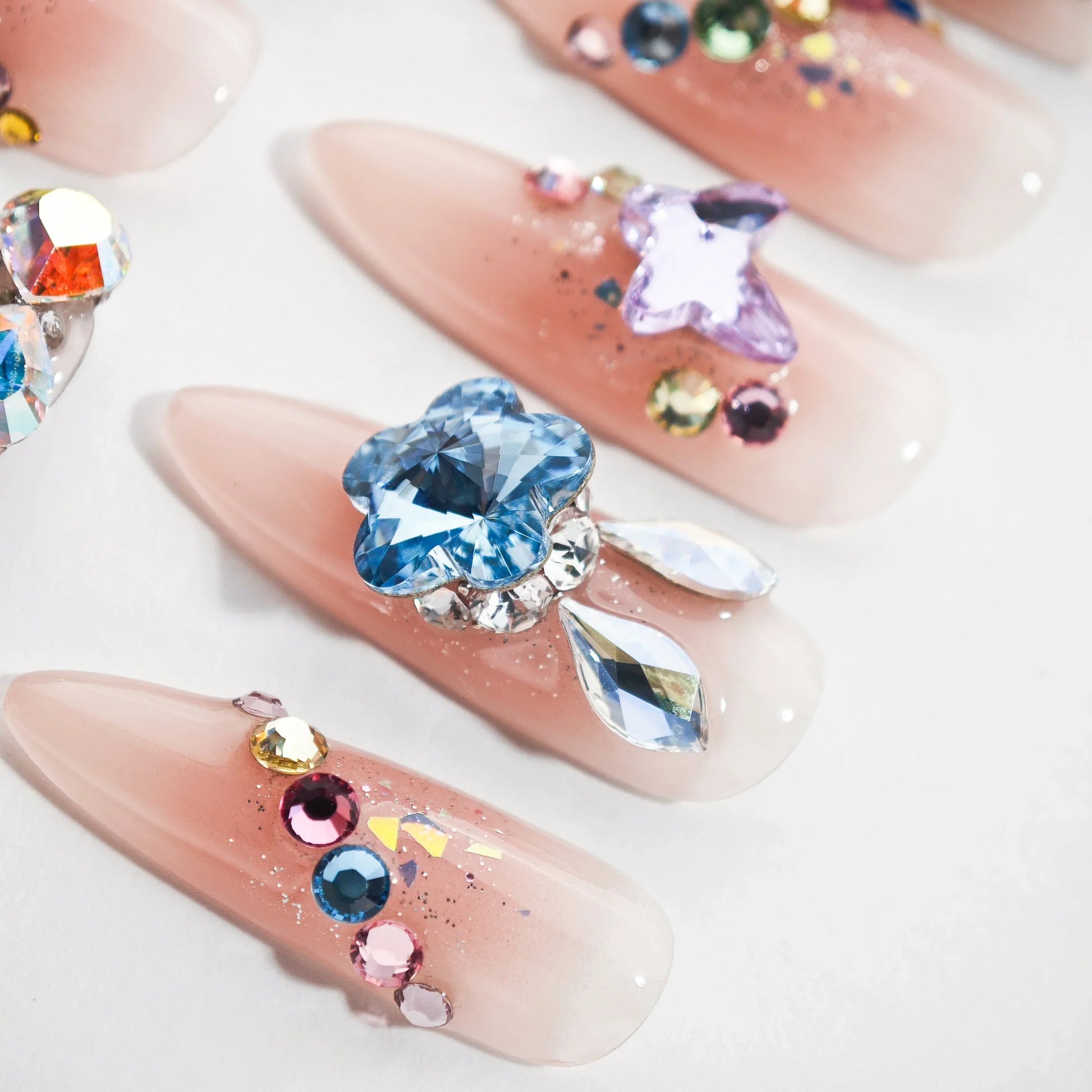 Set of nude pink false nails decorated with colorful rhinestones and floral gems