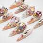 Handmade press-on nails with pink, gold, and crystal gem embellishments on a white background